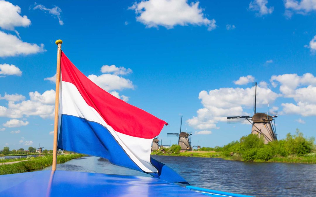 Nationale Molendag: Boot met Nederlandse vlag, met op de achtergrond de molens van Kinderdijk